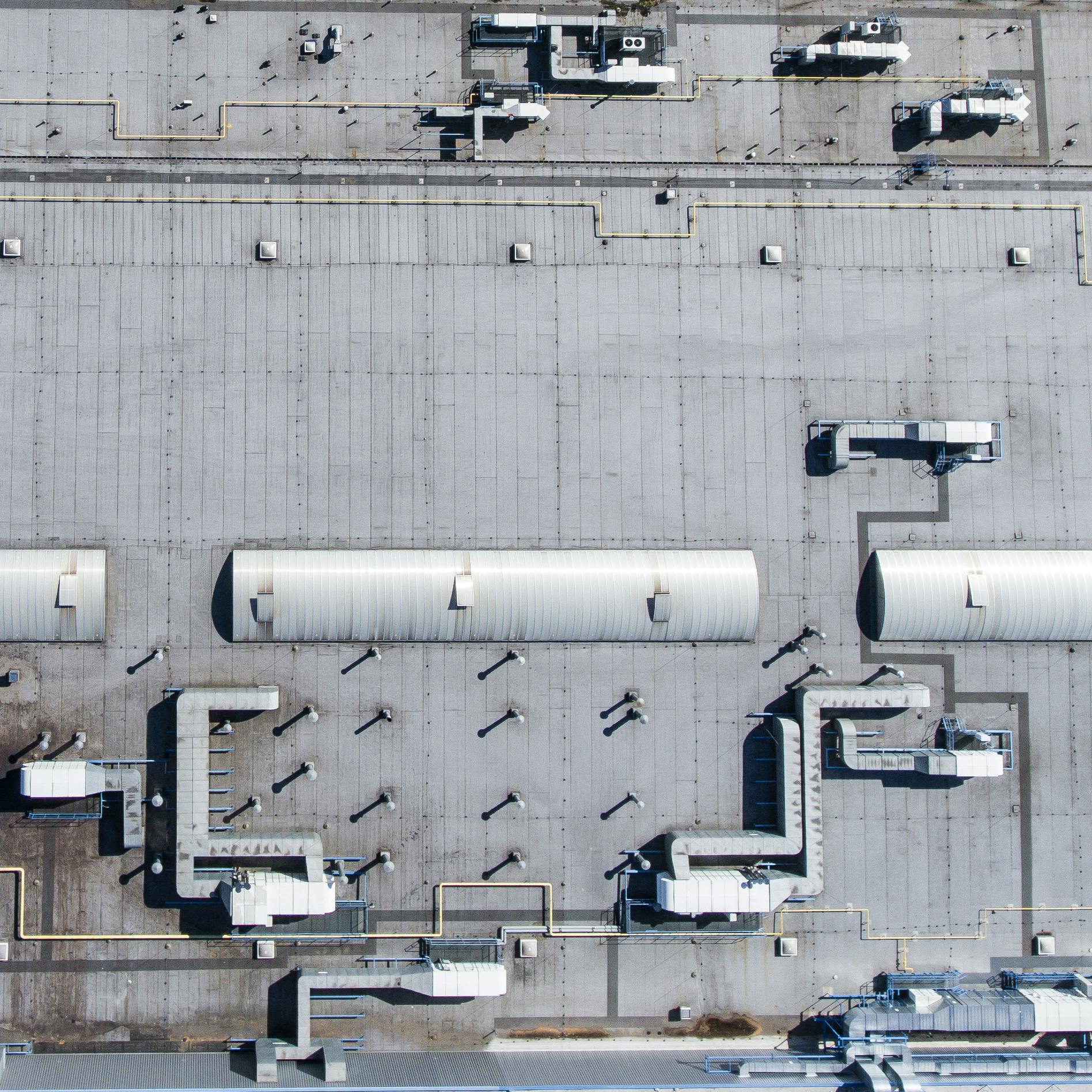 About Aerial top view of a factory roof showcasing industrial pipes and structures.